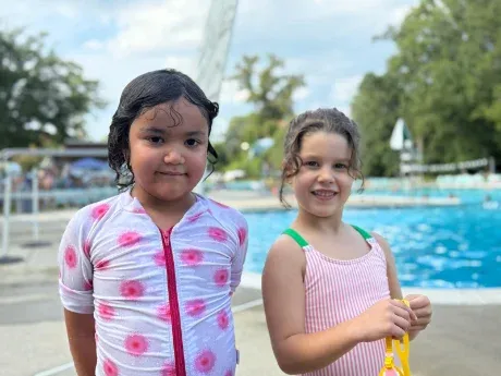 Two pen pals smiling together by a pool