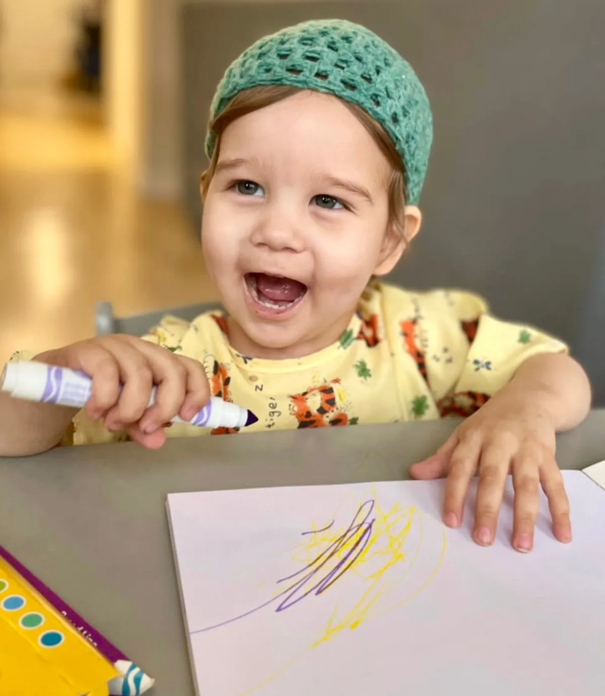 Toddler laughing while drawing a letter